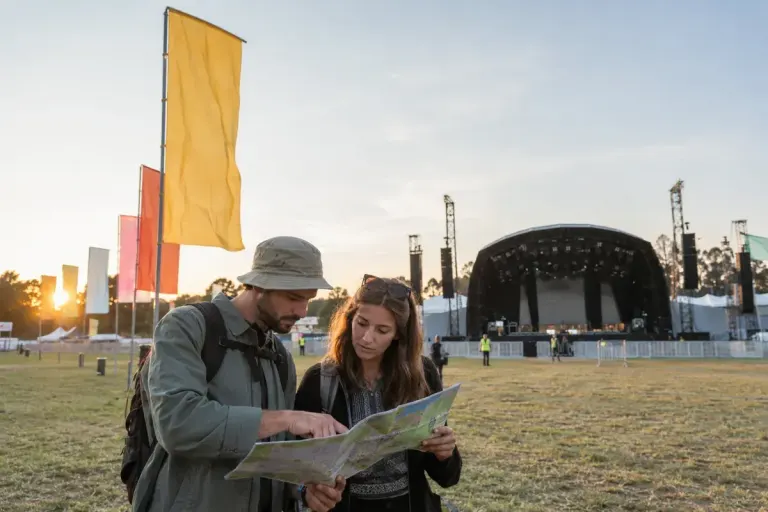 Two adult festival visitors checking a map beside a distinctive flag.